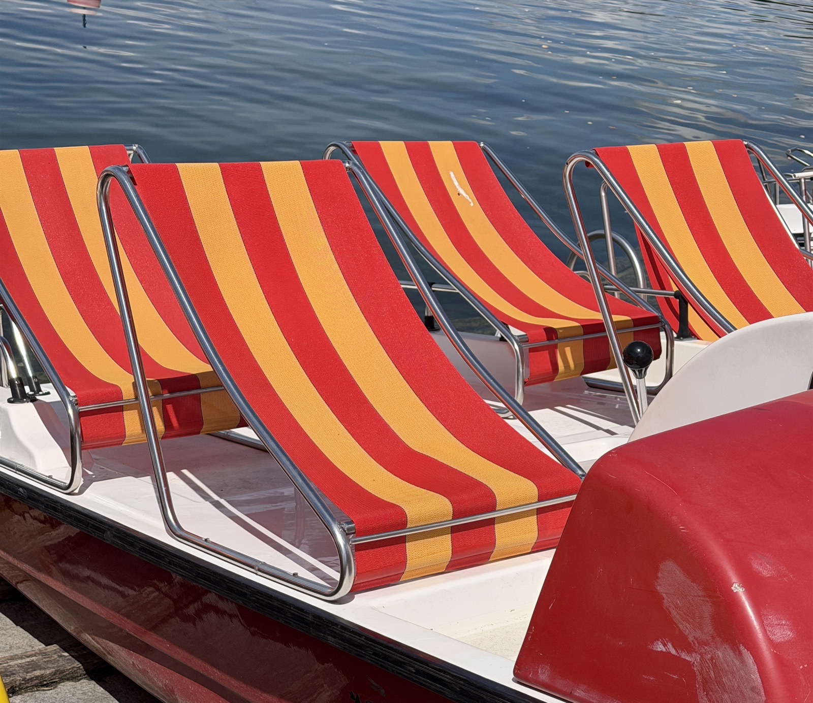 Red and yellow striped pedalo seats on the lake